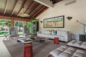 A spacious living area with a high ceiling, a sofa set, a coffee table, and a painting on the wall. - Casa de Campo Golf View Villa (La romana)