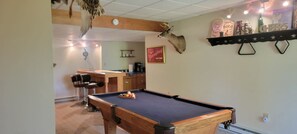 A pool table in a room with a wooden ceiling, a mounted deer head, and a shelf with various items. - Huntzinger Hideaway: Furnished 1 Bdrm apartment (Wernersville)