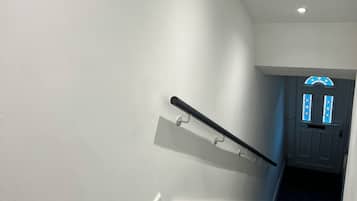 En trappa med ett ledstång, steg klädda med matta och en dörr med ett blått, färgat glasfönster.