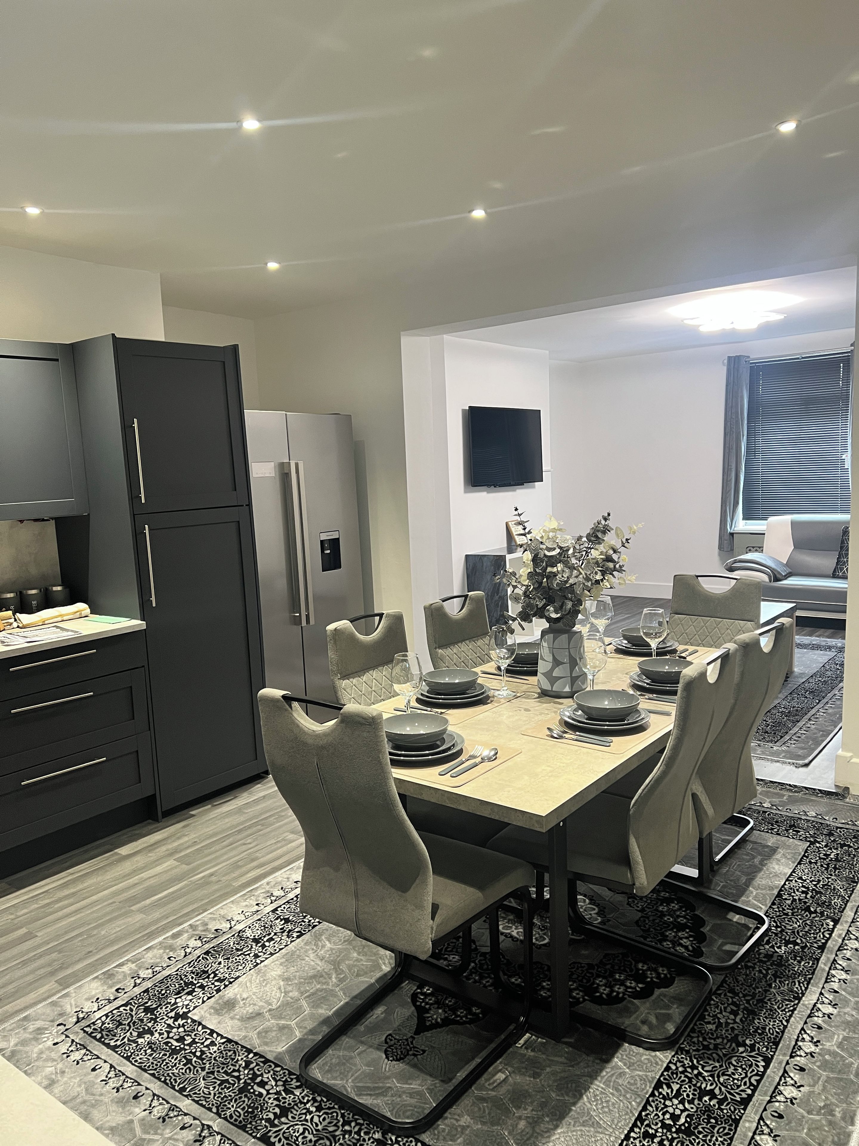 Un comedor moderno con una mesa rectangular dispuesta para cuatro personas, rodeada de sillas acolchadas.