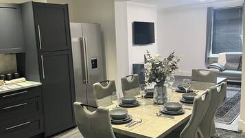 Un comedor moderno con una mesa rectangular dispuesta para cuatro personas, rodeada de sillas acolchadas.