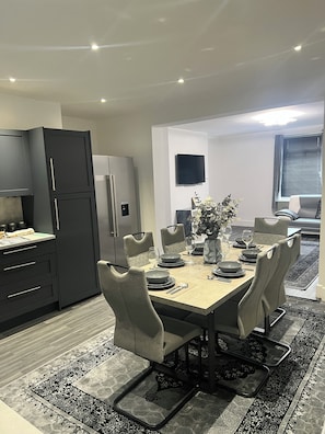 A modern dining area with a rectangular table set for four, surrounded by cushioned chairs.