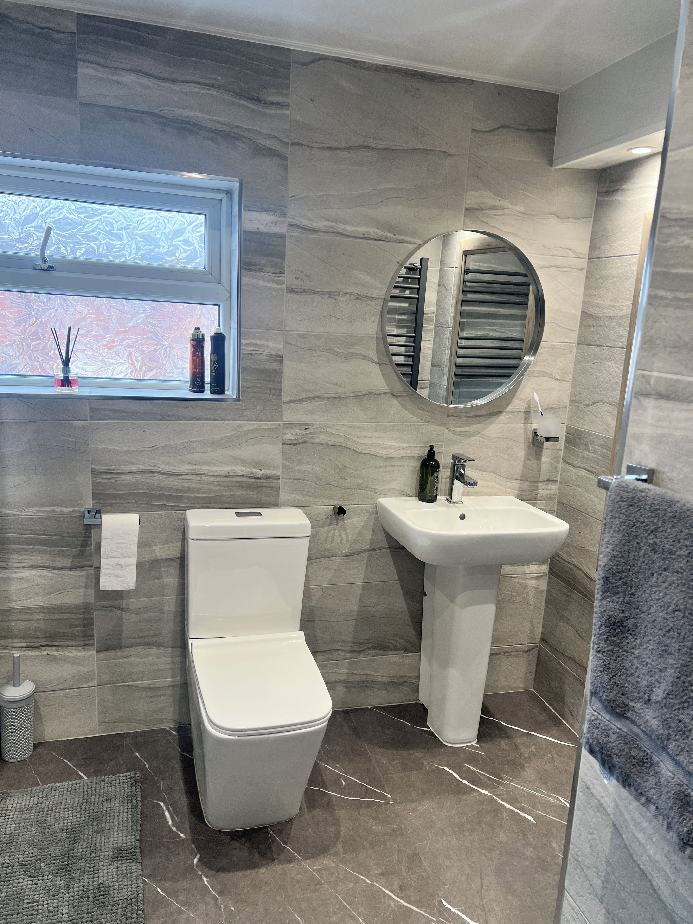 A modern bathroom with a toilet, sink, and a window with decorative items.