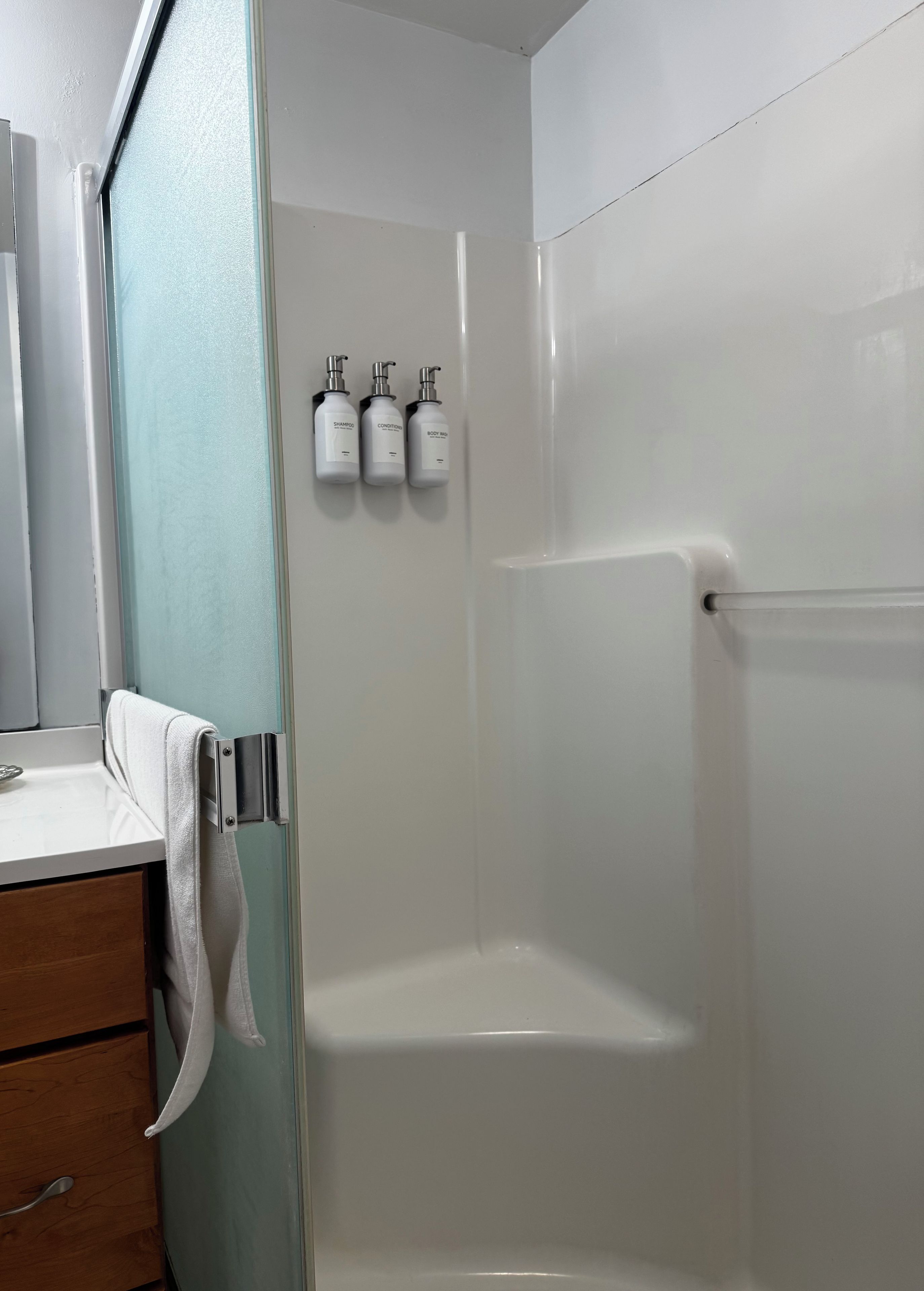 A bathroom with a white sink, a towel rack, and three bottles of toiletries.