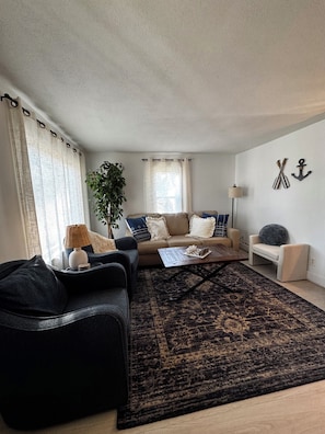 A living room with a sofa, a coffee table, a lamp, a plant, and a rug. - Culver Cottage: Walk to the lake, downtown & academies (Culver)