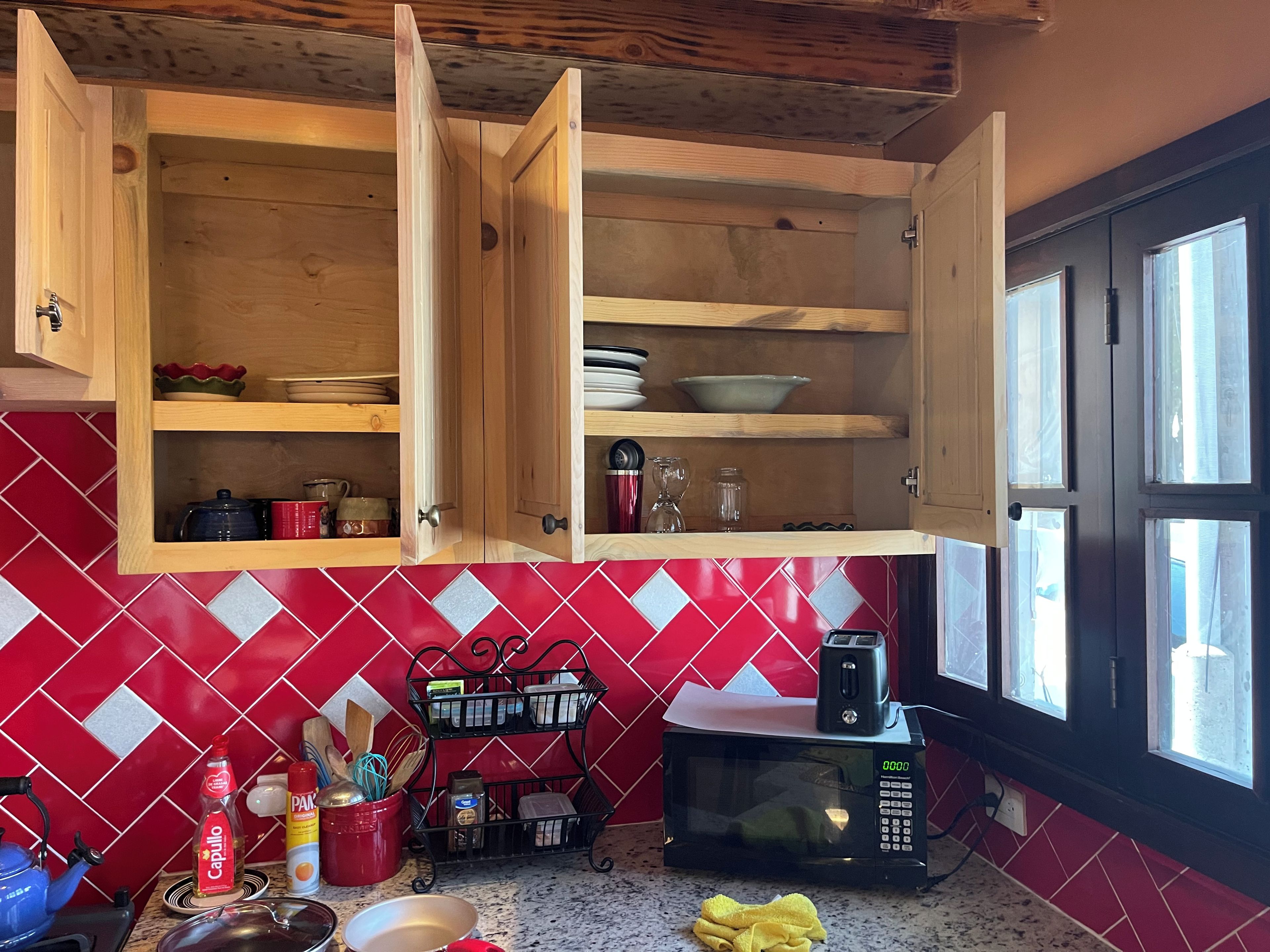 A kitchen with wooden cabinets, a microwave, and a red-tiled backsplash.