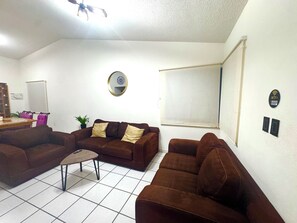 A living room with two sofas, a coffee table, a plant, a wall clock, a whiteboard, and a WiFi sign. - Lomas Cocoyoc Private pool / barbecue / Wi-Fi / pet-friendly (Fraccionamiento Lomas de Cocoyoc)