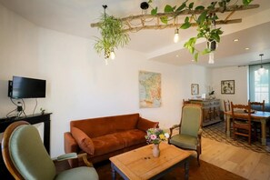 A living room with a sofa, armchair, coffee table, and hanging plants. - THE KEYS TO THE EMERALD (BERGNICOURT)