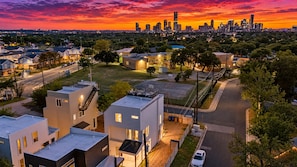 A residential area with modern houses, a clear road, and a distant city skyline at sunset. - Austin Escape w/ Private Patio Near Lady Bird Lake (Austin)