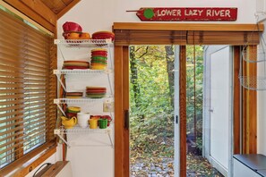 Eine Küche mit Holzhörchen, einem Schild mit der Aufschrift 'LOWER LAZY RIVER' und Regalen voller bunter Geschirr.