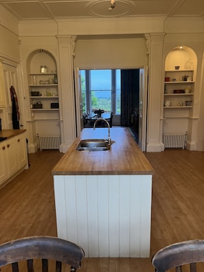 A kitchen with a central island, wooden cabinets, and a view through an open door.