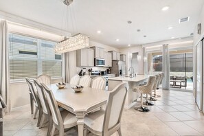 A modern kitchen with a dining area, large windows, and a view of the outdoors. - 5BR/5.5BA Clermont Home w/ Resort Pool & Golf (Clermont)