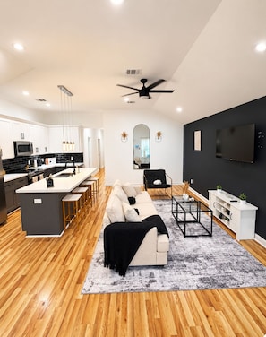 A modern kitchen with white cabinets, a black countertop, and a built-in microwave. - Modern 3BR Houston Escape in the Heart of HTX (Houston)