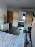 Un dormitorio con cama, cómoda, espejo y ventana.