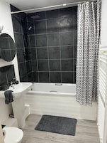 Un baño con bañera, ducha, lavabo e inodoro.