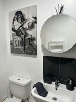 Un baño con inodoro, lavamanos y espejo, con una toalla colgada.