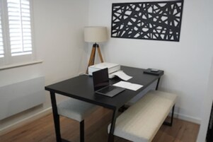 Un espacio de oficina moderno con escritorio, ordenador portátil, lámpara y decoración mural.