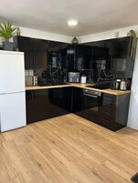 Una cocina moderna con armarios negros, un refrigerador blanco y una encimera de madera.