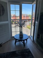 Una habitación con vistas, una puerta de vidrio, una mesa redonda con un florero y un sofá verde.