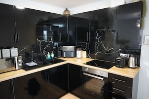 Una cocina moderna con armarios negros, encimera negra y horno empotrado.