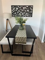 Una mesa de comedor con un mantel de diseño geométrico, un jarrón con flores y una obra de arte moderna en la pared.
