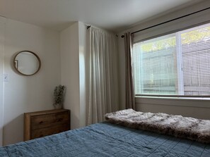 A bedroom with a bed, a dresser, a mirror, and a window with blinds. - Cozy Walkable "Cottage" Home (Coeur d'Alene)