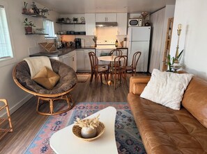 A compact living space with a dining area, a sofa, a chair, and a kitchen in the background. - Cozy Walkable "Cottage" Home (Coeur d'Alene)