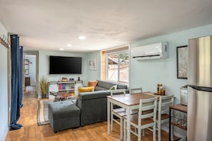 Un espacio habitable compacto con sofá, mesa de comedor y televisor de pantalla plana montado en la pared.