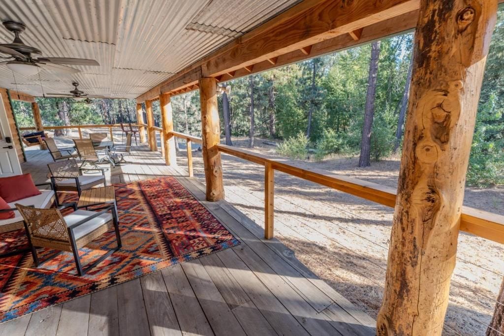 A covered outdoor deck with seating and a patterned rug.