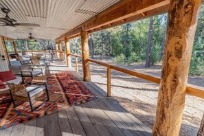A covered outdoor area with wooden flooring, a patterned rug, and seating furniture. - Pinecone Hideaway Peppermint Falls (Springville)