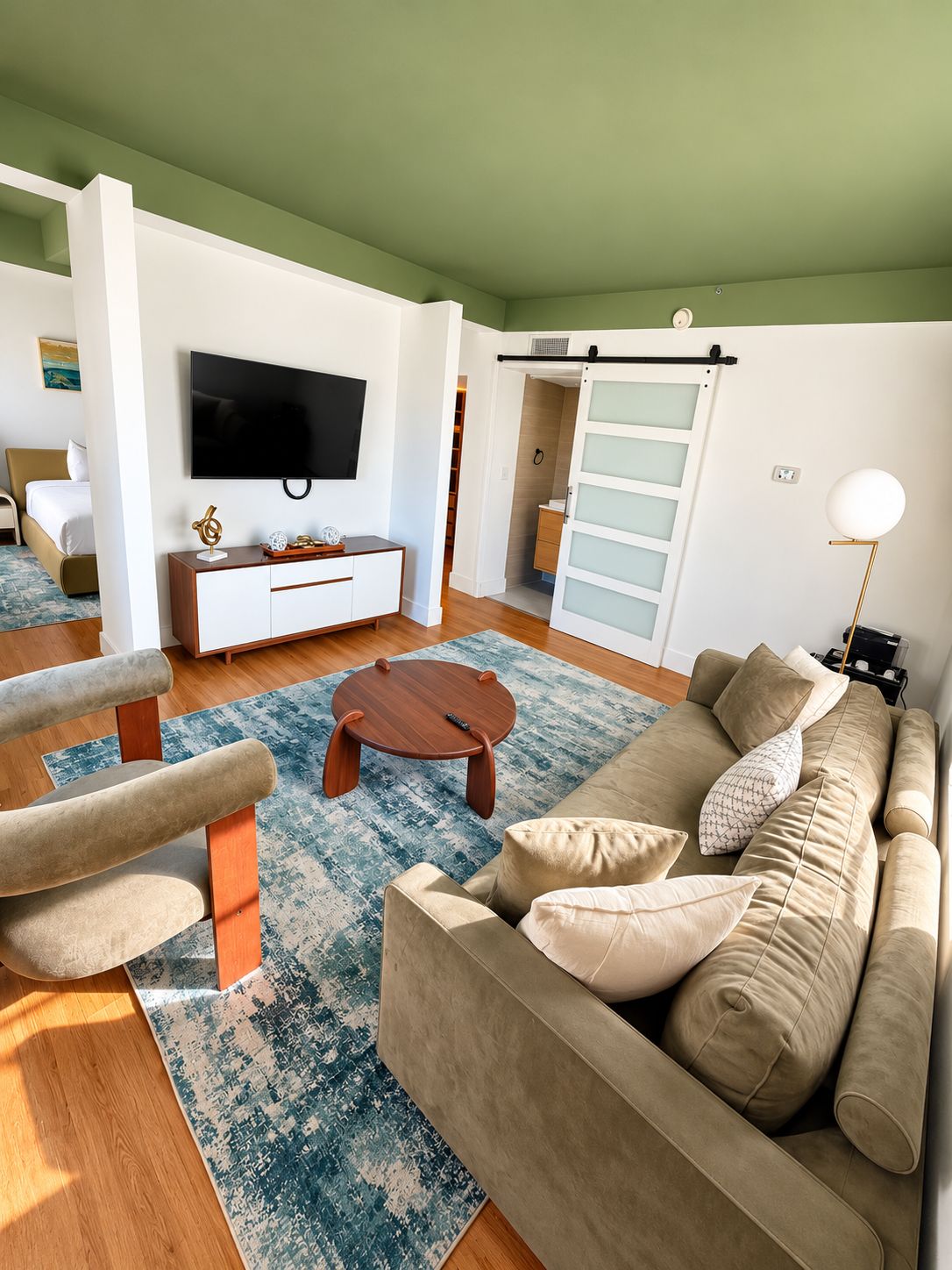 A modern living room with a sofa, armchair, coffee table, and a TV mounted on the wall.