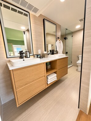 A modern bathroom with a large mirror, a white sink, and a glass shower enclosure. - Deluxe King Suite, Beach Access & Prime Location (Miami Beach)