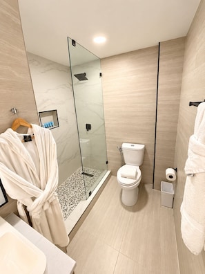 A modern bathroom with a glass-enclosed shower, a toilet, and a sink. - Deluxe King Suite, Beach Access & Prime Location (Miami Beach)