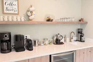 Eine Küche mit einer Kaffeestation, darunter mehrere Kaffeemaschinen und ein Kaffeetassenhalter.