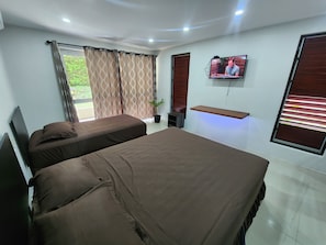 A hotel room with two beds, a television, a potted plant, and a window with curtains. - Tropic Towers Apartments Hotel (Suva)
