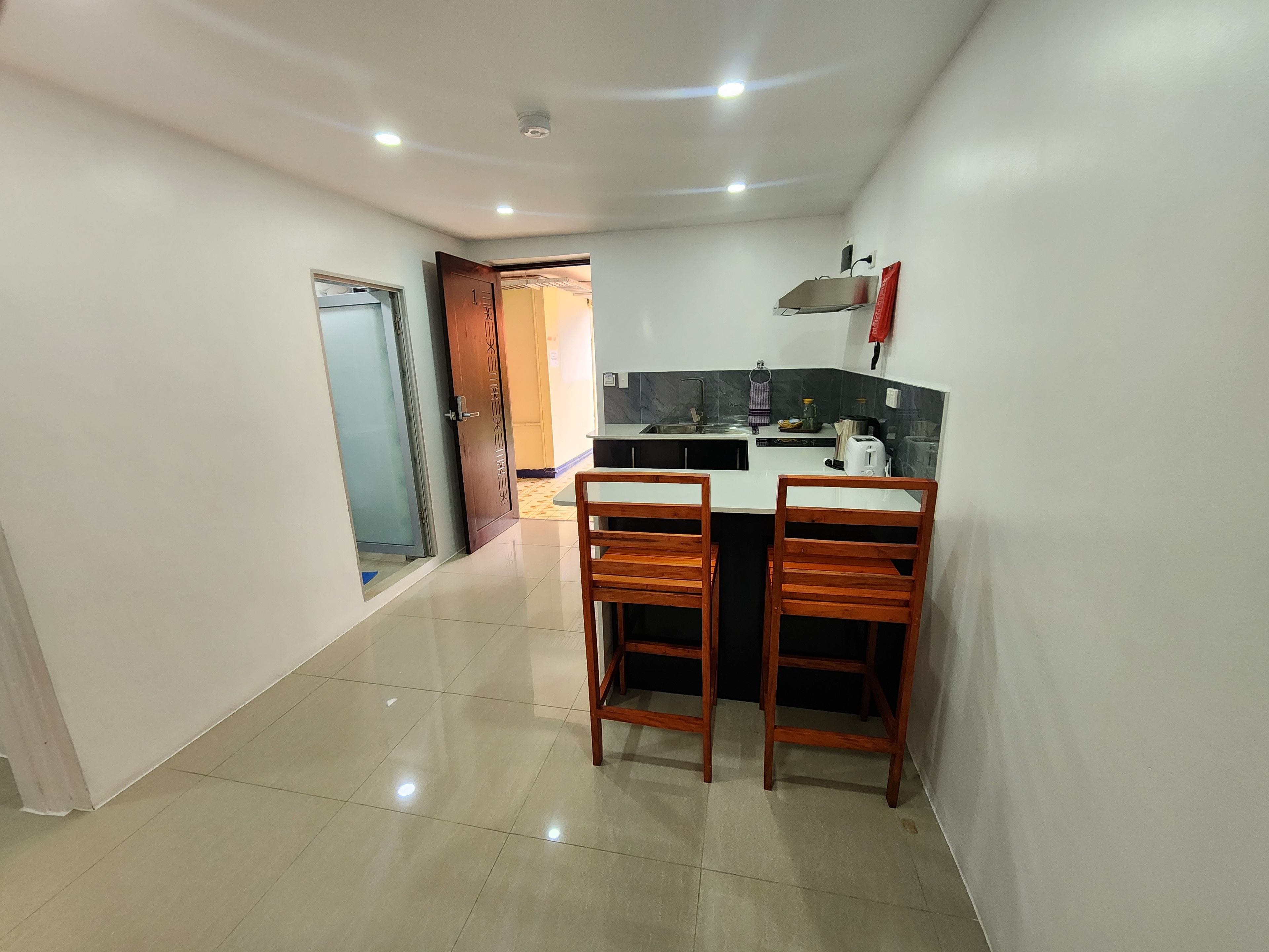 A compact kitchen with a dining area, featuring a small island, two wooden chairs, and a built-in sink.