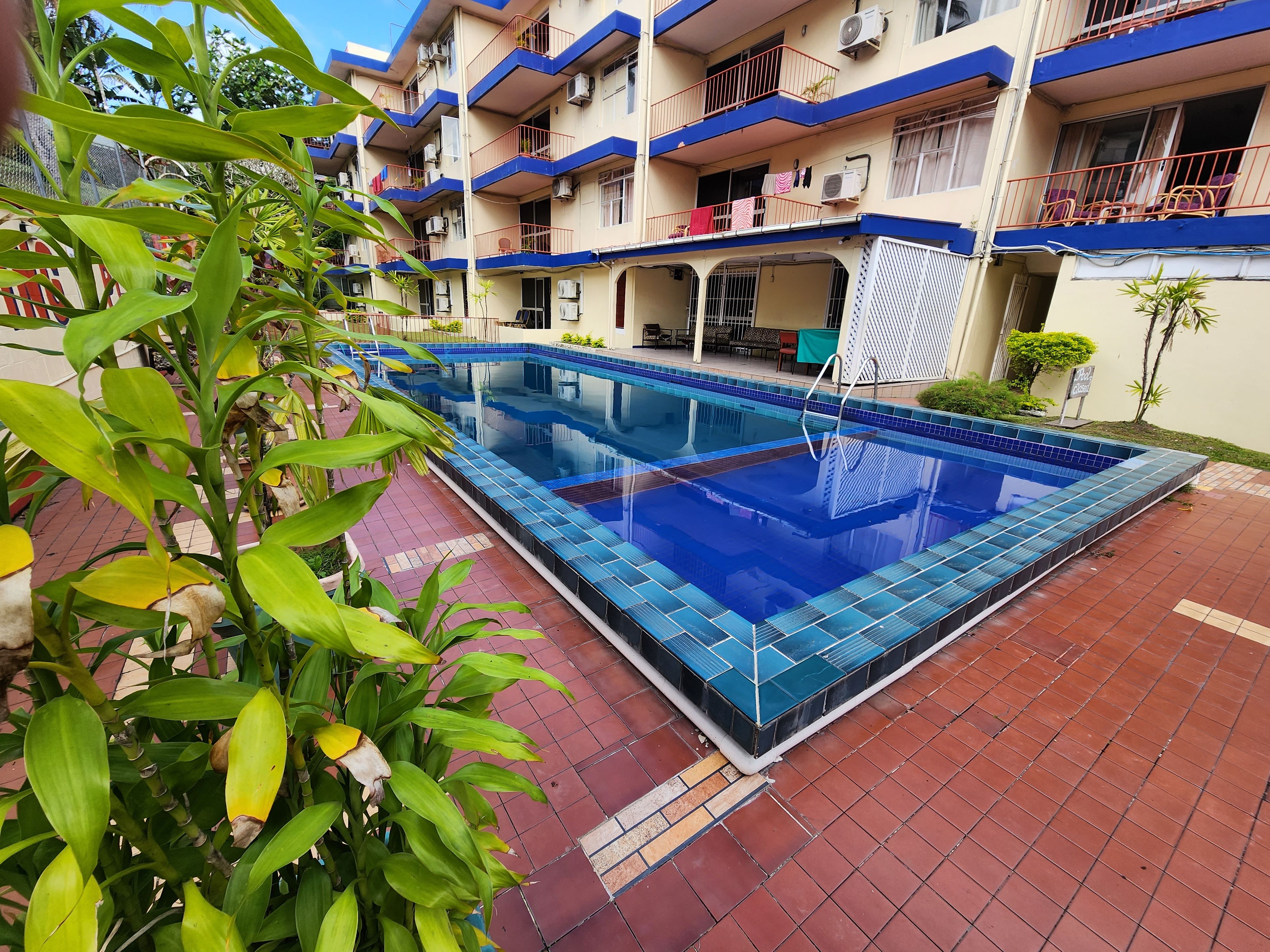 A swimming pool with a tiled edge, surrounded by a red-tiled patio.