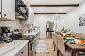 A modern kitchen with a built-in oven, a coffee machine, and a refrigerator. - Spacious 5BR Tacoma Home - Sleeps 9 - Hilltop -Fenced Yard + Playroom (Tacoma)