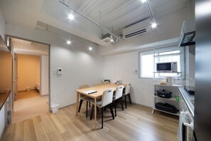 A modern kitchen with a dining area, wooden flooring, and built-in appliances. - METRO GATE OSAKA (Osaka)