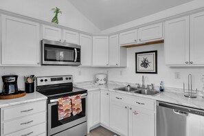 A kitchen with white cabinets, a microwave, an oven, a coffee maker, and a dishwasher. - 2BR Marathon home with private pool (Marathon)
