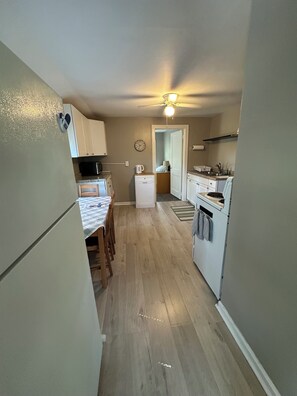 A compact kitchen with a refrigerator, a microwave, a sink, and a dining area with a table and chairs. - 2-Bedroom Upper Unit Duplex on Quiet Street in Roseville (Roseville)