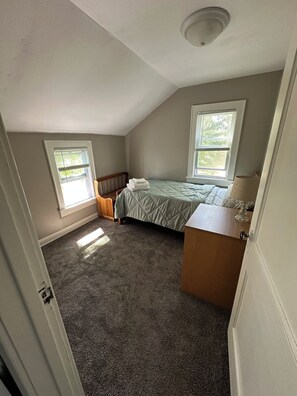 Une chambre à coucher avec un lit, une commode et une fenêtre.