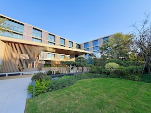 A modern hotel with a glass facade, a covered entrance, and a well-maintained garden. - SUNSHINE HOTEL (Hangzhou)