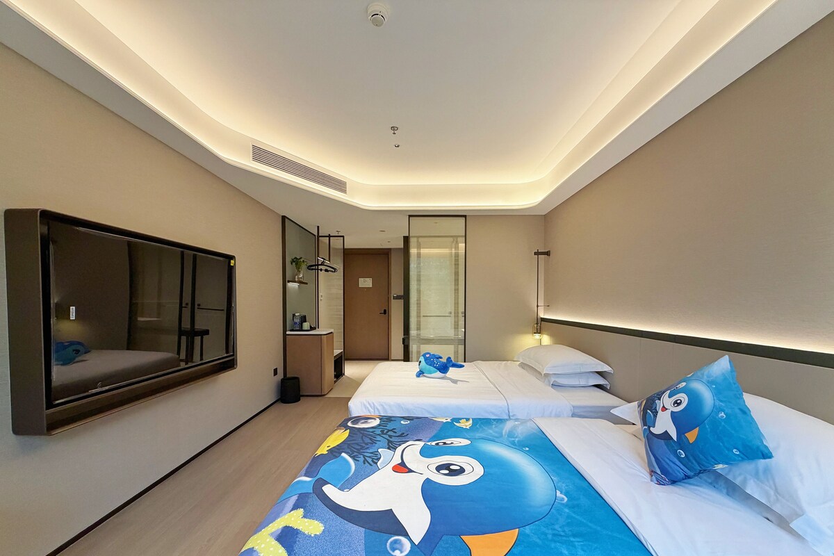 A hotel room with a large bed, a bedside table, a mirror, a TV, and a bathroom door.