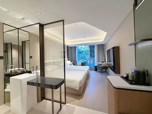 A modern hotel room with a large bed, a separate sitting area, a bathroom with a vanity, and a large mirror. - SUNSHINE HOTEL (Hangzhou)