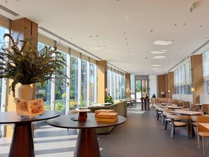 A spacious indoor area with large windows, modern furniture, and a central plant arrangement. - SUNSHINE HOTEL (Hangzhou)