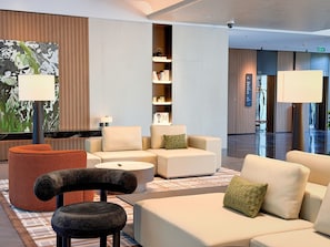 A modern lobby with seating arrangements, a reception desk, and a bookshelf. - SUNSHINE HOTEL (Hangzhou)