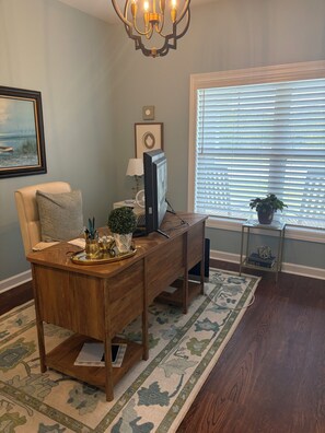 A wooden desk with a computer, a lamp, and decorative items. There is a chair with a patterned cushion, a framed picture on the wall, and a window with blinds. - Private 50-Acre Executive Retreat in Sumter, SC 12 Min to Courthouse (Sumter)