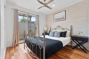 A bedroom with a bed, bedside table, and a ceiling fan. - The Family Haven Sea Villas - Studio 1 & 2 (Rye)