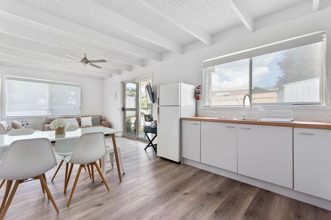A modern kitchen with white cabinetry, a wooden countertop, and a large window.